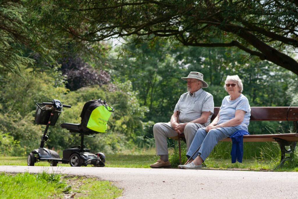 An old couple sitting on a bench and a bike beside them